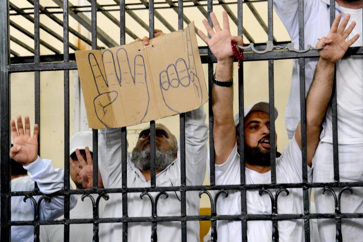 In a May 19 photo, supporters of the Muslim Brotherhood and other Islamists hold a cardboard sign with the "rabaa" symbol as they receive sentences ranging from eight to 15 years in prison to death by hanging.