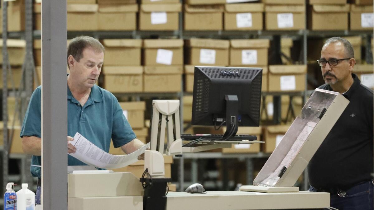 Employees run ballots through a machine before resuming a recount Thursday at the Palm Beach County Supervisor of Elections office in West Palm Beach, Fla.