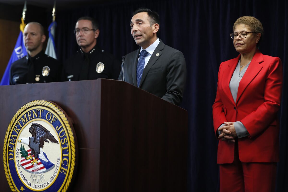 At right, Karen Bass, and Martin Estrada, second to right, and two police officers standing behind a lectern