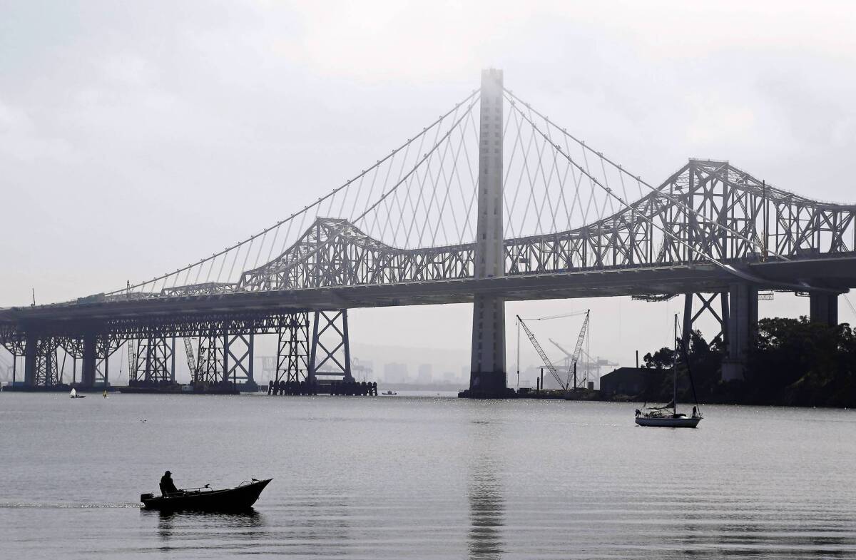 Boats make their way past the eastern span replacement of the San Francisco-Oakland Bay Bridge. Officials decided that the $6.3-billion span, which parallels the existing bridge, cannot open over Labor Day weekend as planned.