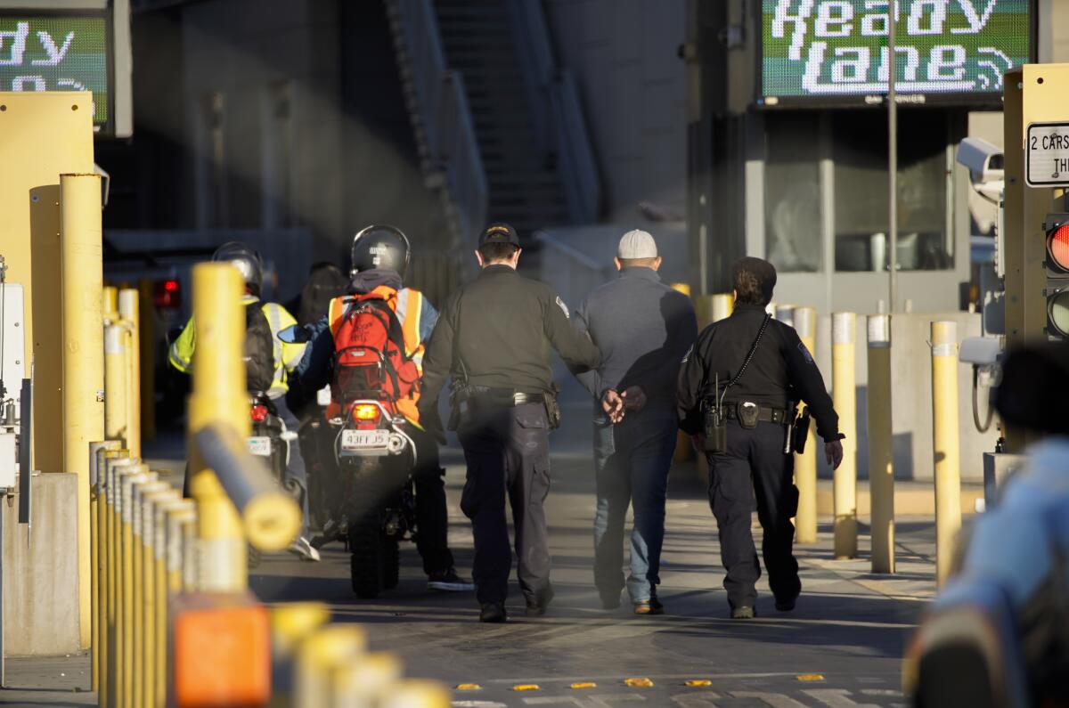 A man is handcuffed and taken into custody by U.S. Customs and Border Protection officers