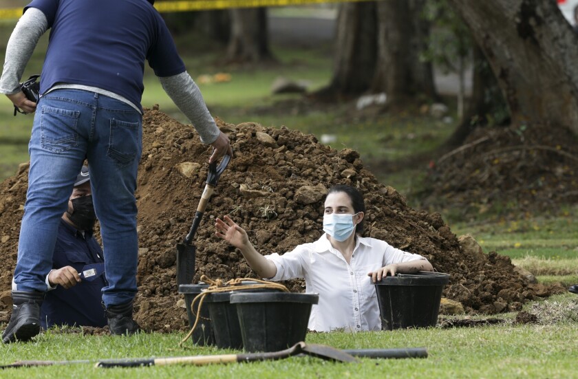 Trabajadores forenses exhuman lo que se cree que son los restos del teniente Braulio Bethancourt, víctima de la invasión estadounidense de 1989, en el cementerio Jardín de Paz de la ciudad de Panamá, el jueves 15 de abril de 2021. (AP Foto/Arnulfo Franco)