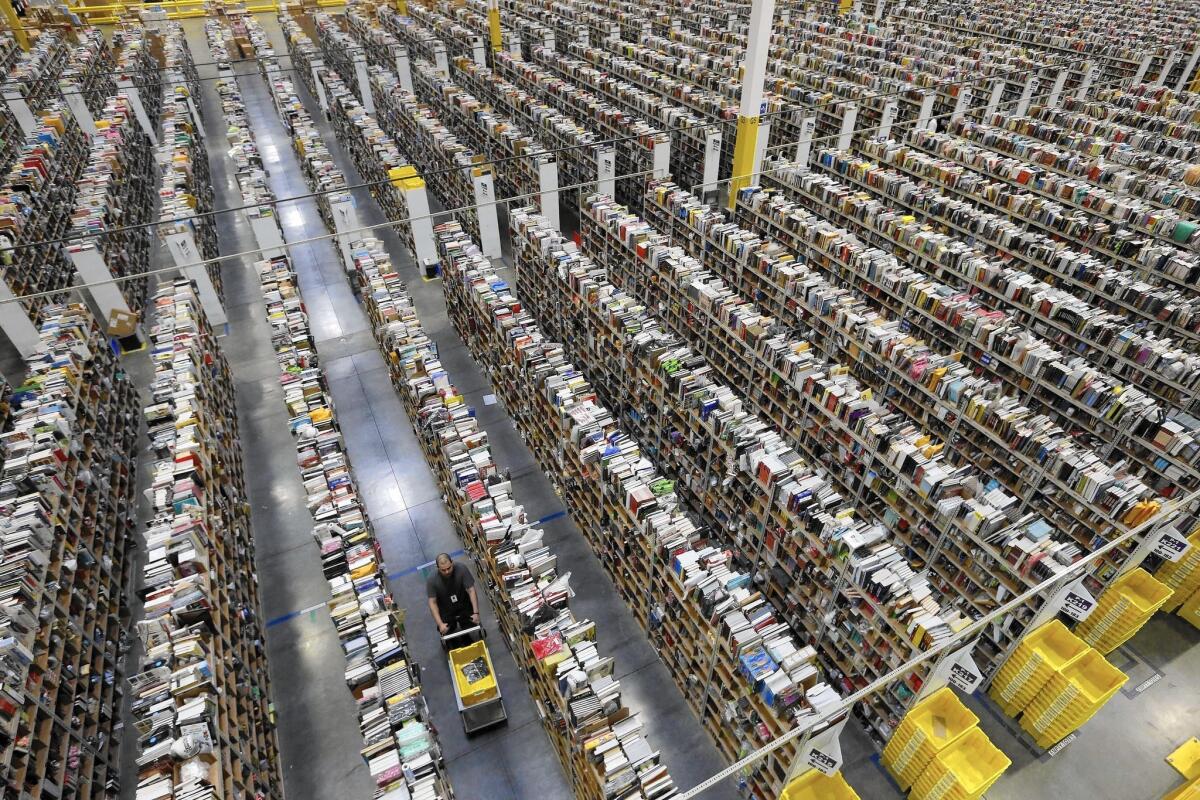 Amazon workers have complained about a punishing work culture in which employees work nights and weekends. Above, a worker walks down one of the miles of aisles at Amazon’s fulfillment center in Phoenix.