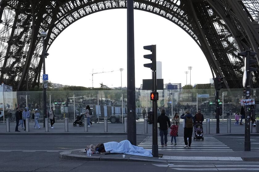 FILE - A homeless sleeps just next to the Eiffel Tower Wednesday, April 10, 2024 in Paris. With the Paris Games 100 days away, French police carried out a large-scale eviction at an abandoned factory, located on the southern outskirts of Paris in Vitry-sur-Sein on Wednesday, April 17, 2024. (AP Photo/Laurent Cipriani , File)