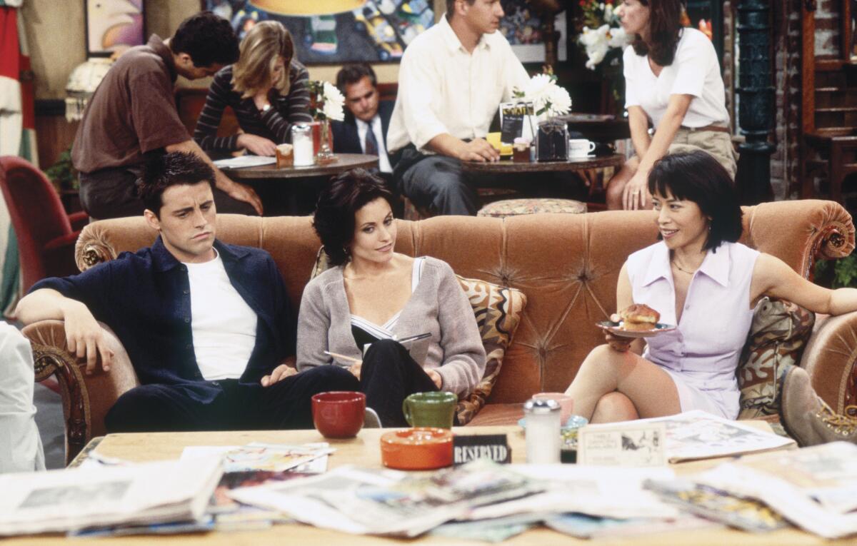 Matt Le Blanc as Joey Tribbiani, Courteney Cox as Monica Geller, Lauren Tom as Julie  sit on the couch at the Central Perk.