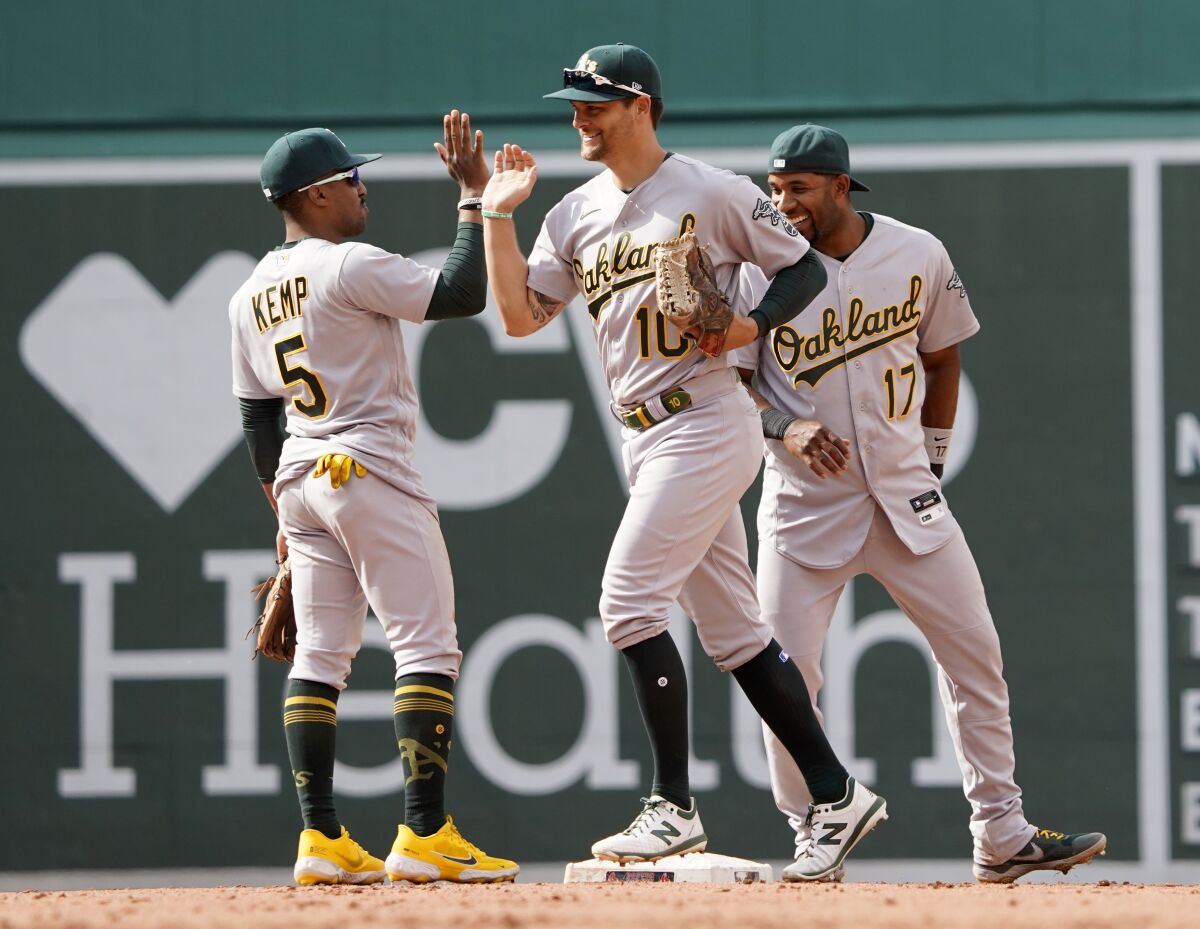 Oakland Athletics players, from left, Tony Kemp (5), Chad Pinder, and Elvis Andrus (17) celebrate after defeating the Boston Red Sox in a baseball game at Fenway Park, Thursday, June 16, 2022, in Boston. (AP Photo/Mary Schwalm)
