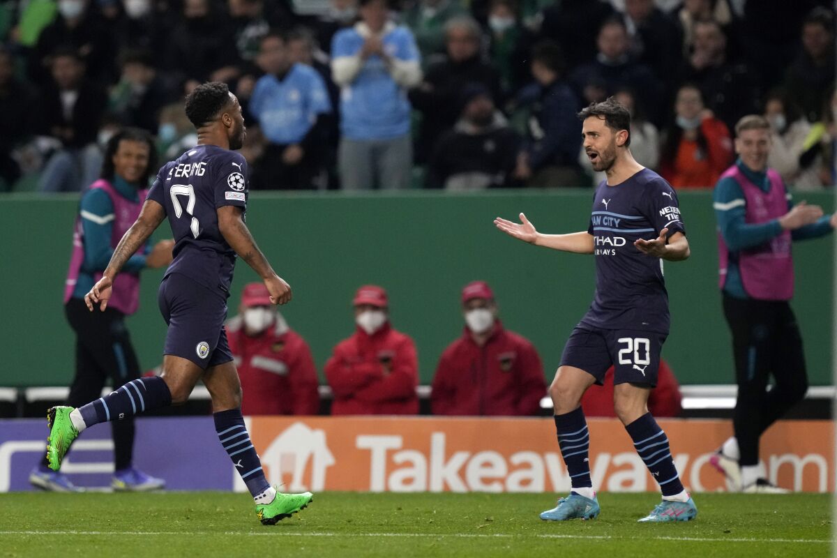 Manchester City's Raheem Sterling, left, celabrates with Bernardo Silva, his side's fifth goal during the Champions League round of 16 soccer match between Sporting CP and Manchester City at the Alvalade stadium in Lisbon, Portugal, Tuesday, Feb. 15, 2022. (AP Photo/Armando Franca)