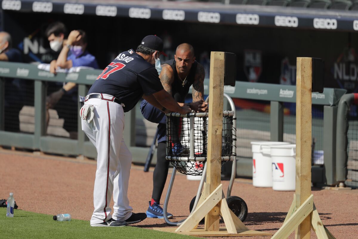 FILE - In this July 5, 2020, file photo, Atlanta Braves' Nick Markakis, right, talks with a coach during team practice at Truist Park in Atlanta. Braves outfielder Nick Markakis has opted out of the 2020 season. The 36-year-old Markakis said he was uneasy about playing the season without fans and then was swayed by his telephone conversation with teammate Freddie Freeman, who has tested positive for COVID-19 and has fever and other symptoms. (AP Photo/Brynn Anderson, File)