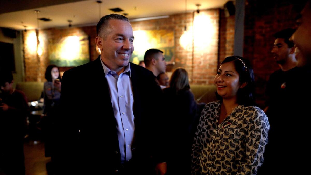Retired Sheriff's Lt. Alex Villanueva, left, gathers with supporters on election night at Cities Restaurant in Los Angeles. He held a razor-thin lead over incumbent Sheriff Jim McDonnell.