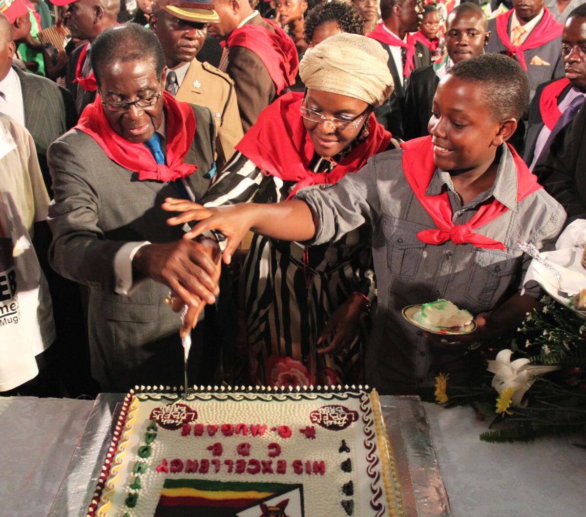 Zimbabwean President Robert Mugabe, left, helps cut his birthday cake, with his wife, Grace, and son Bellarmine Chatunga during celebrations for his 87th birthday.