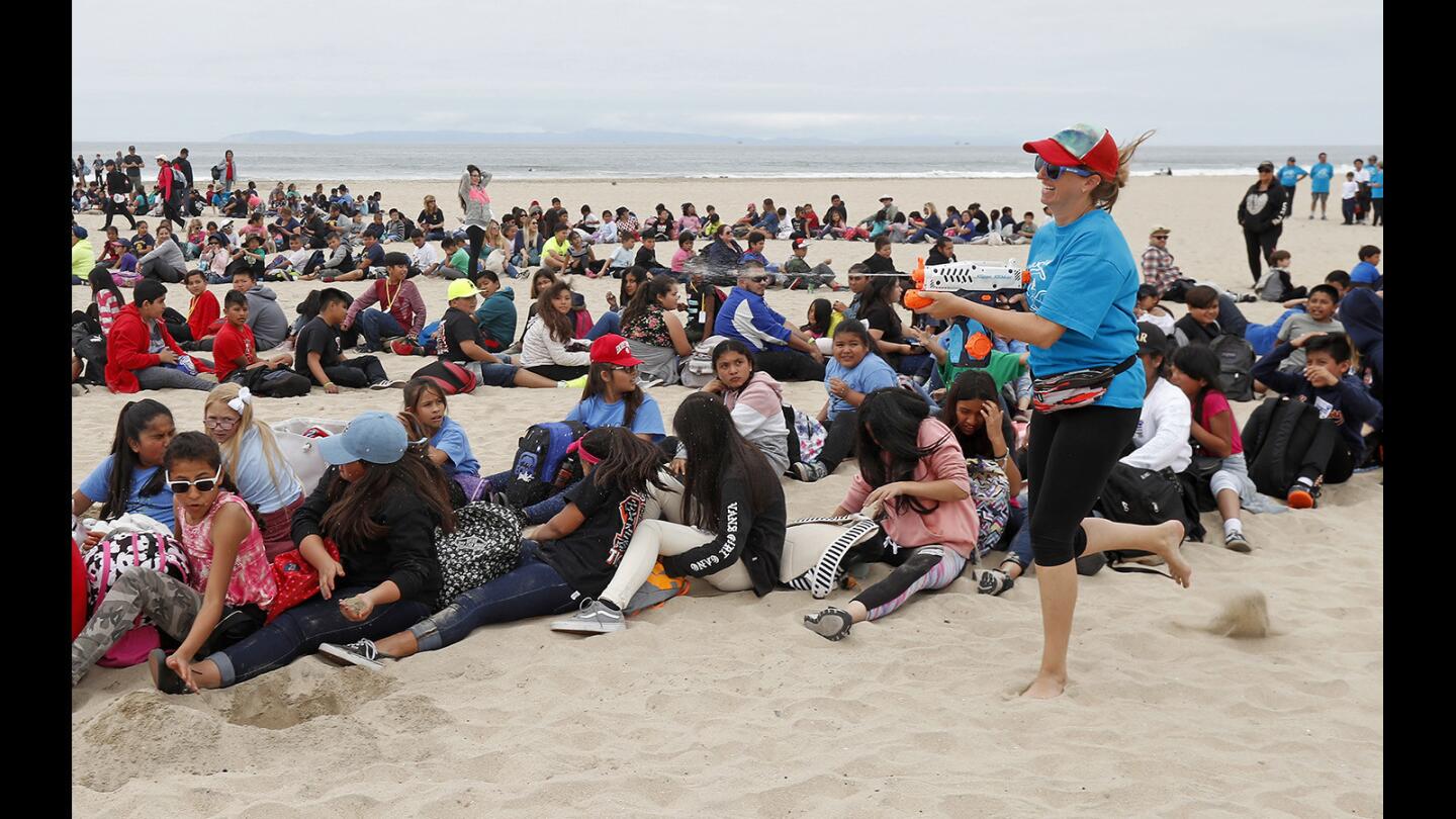 Katie Nichols, marine restoration director for Costa Mesa-based Orange County Coastkeeper, gets students in the spirit of Kids Ocean Day with a little spray as they get in place for an aerial picture during a trash cleanup event Thursday at Huntington State Beach.