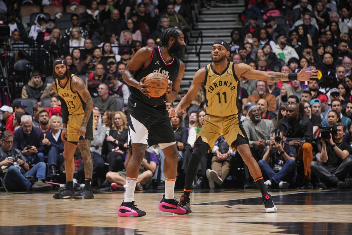 Clippers guard James Harden, left, controls the ball in front of Toronto forward Bruce Brown.