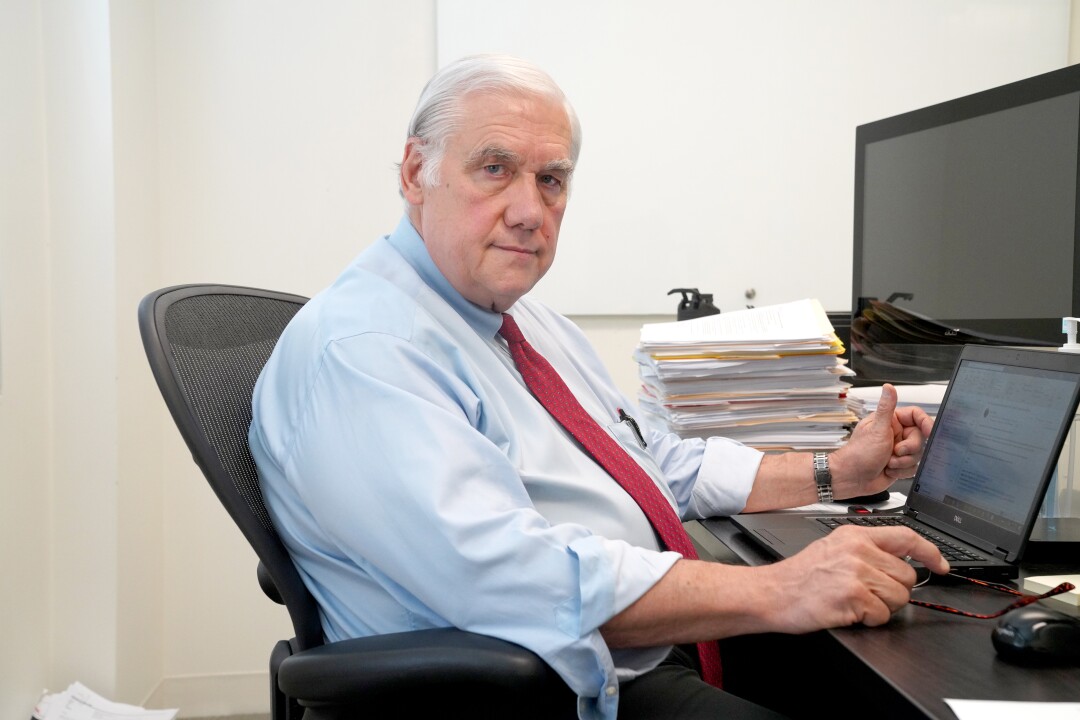 Kenneth Kizer sits in front of a laptop on his desk