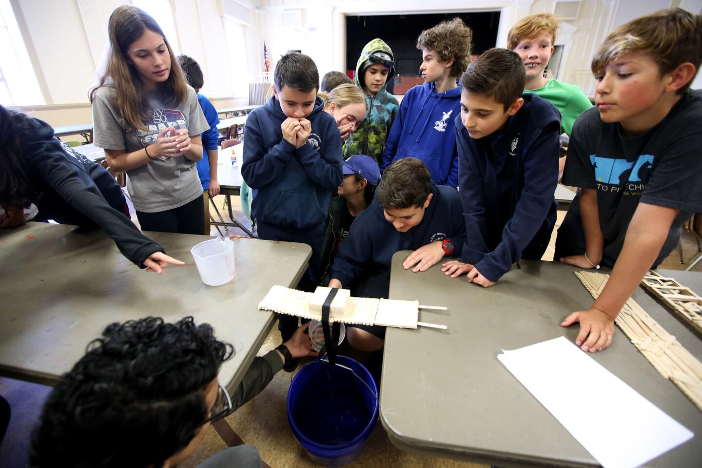 STEM World curriculum director Josue Hernandez helps hold the water container as members of Team Watchdogs test their bridge at the St. John Paul II STEM Academy Camp, at their location in Burbank on Tuesday, May 28, 2019. The bridge was made with 150 wooden craft sticks. Team Watchdogs came in third place.