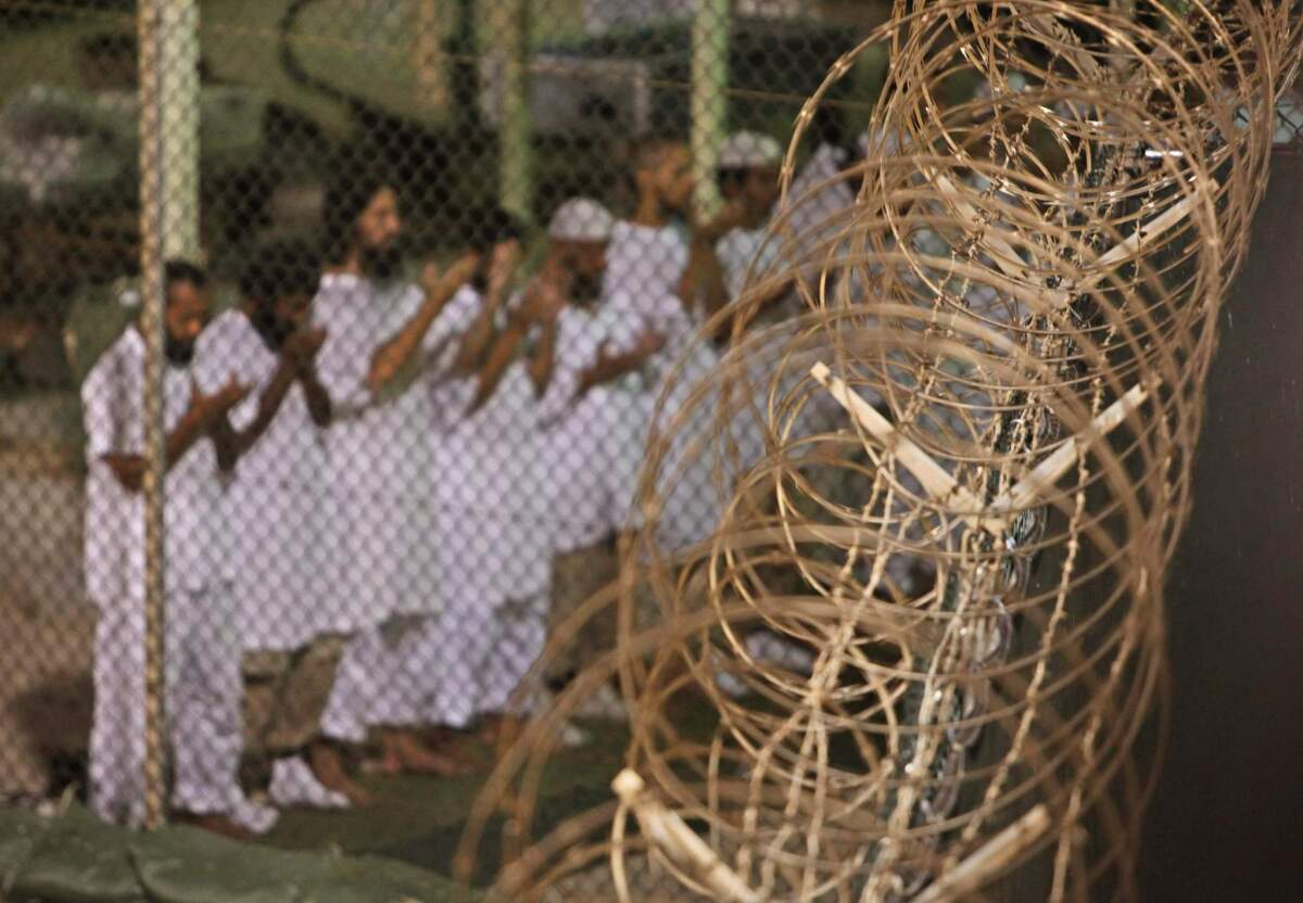 Guantanamo detainees pray before dawn near a fence of razor-wire, inside Camp 4 detention facility at Guantanamo Bay U.S. Naval Base, Cuba.