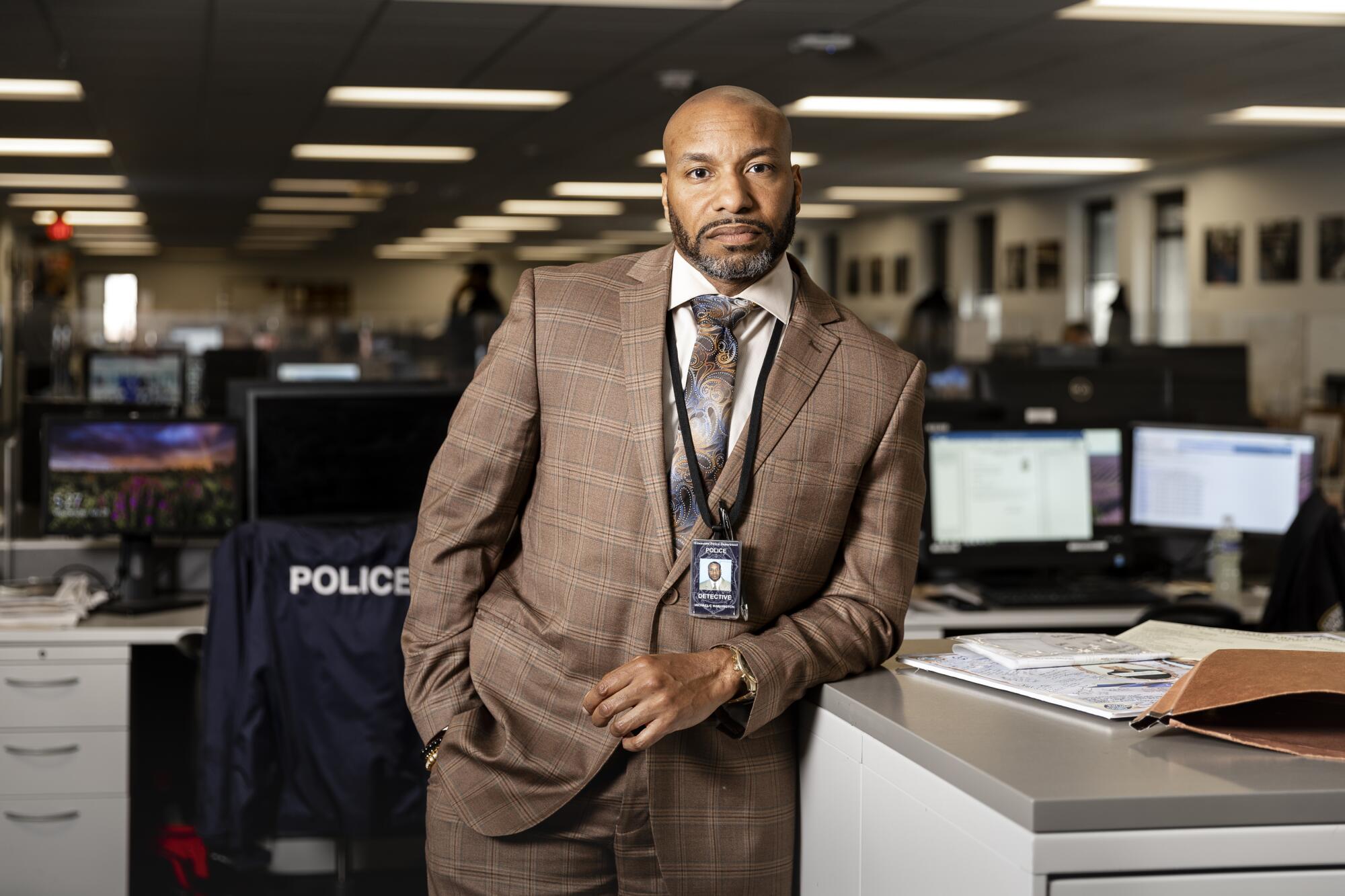 A detective in a suit leans on a filing cabinet