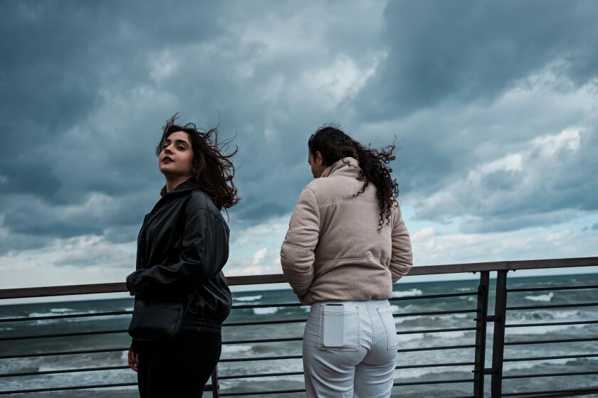 JAFFA, ISRAEL -- JANUARY 27, 2024: Angelina Shakkour, 16, left, and Adar Hirak Asaf, 16, right, visit the beach on a stormy day in Jaffa, Israel, Saturday, Jan. 27, 2024. The teens are 16-year-old girls both friends living in Israel, but unlike a lot of friends, the teens come from opposite sides of one of the worldOs most entrenched political conflicts. Angelina lives in Israel but is a Christian Palestinian. Adar is Jewish. For a long time, it didnOt seem to matter that they didnOt always see eye to eye on politics. Then came the brutal Hamas attack on southern Israel, and IsraelOs months-long retaliatory siege of the Gaza Strip. As the war deepened, they watched as other friends became more entrenched in their views, and as the gap between Palestinians and their Jewish Israeli neighbors dangerously widened. Both admit they sometimes hid their friendship from family members or others who might judge them. Thanks to the unique program that had brought them together in the first place, Angelina and Adar were unusually skilled at navigating differences of opinion. But as the war tore seemingly everything around them apart, a question hovered: Could their friendship survive intact? (MARCUS YAM / LOS ANGELES TIMES)