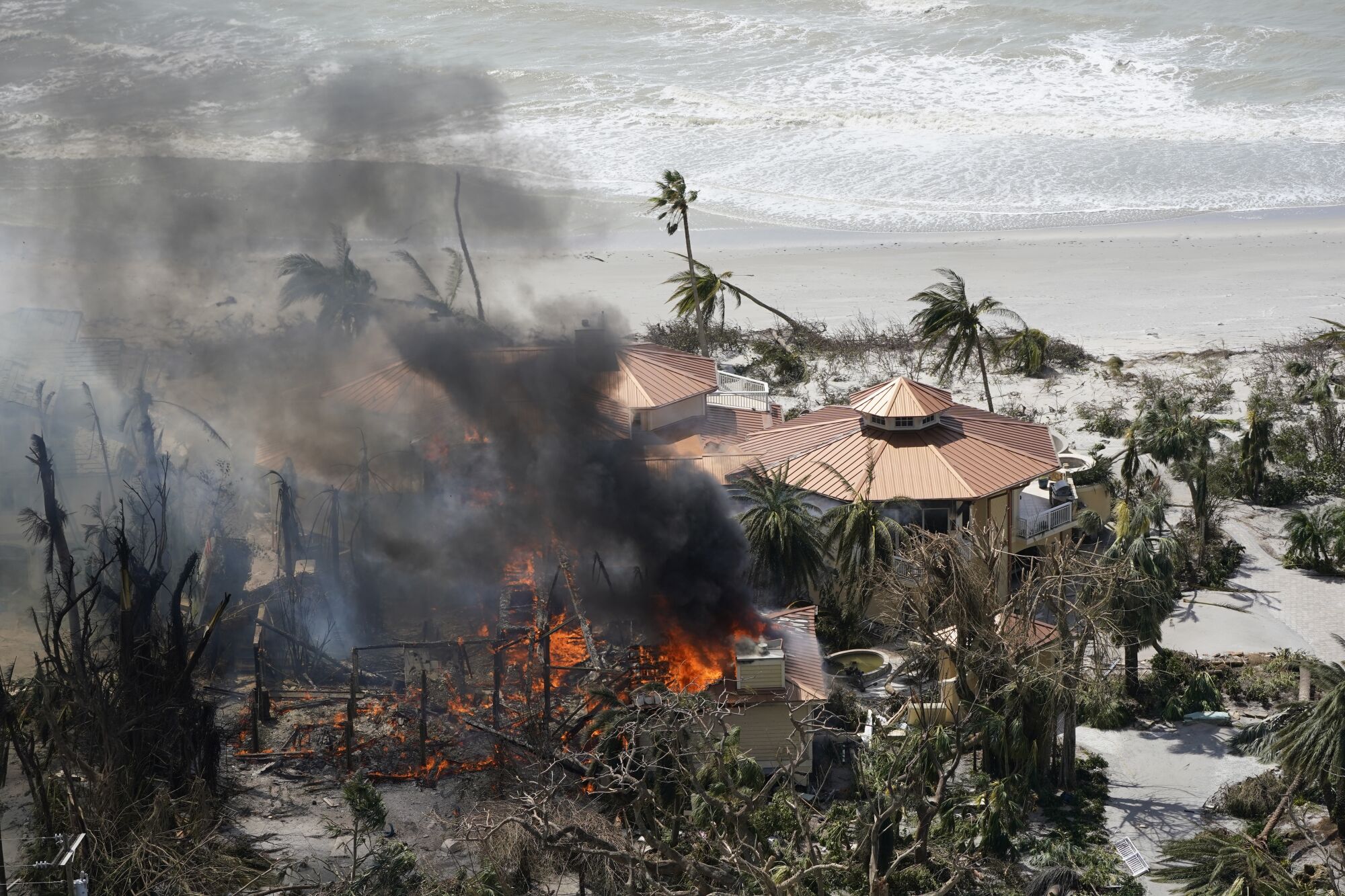 A structure burns by a beach.