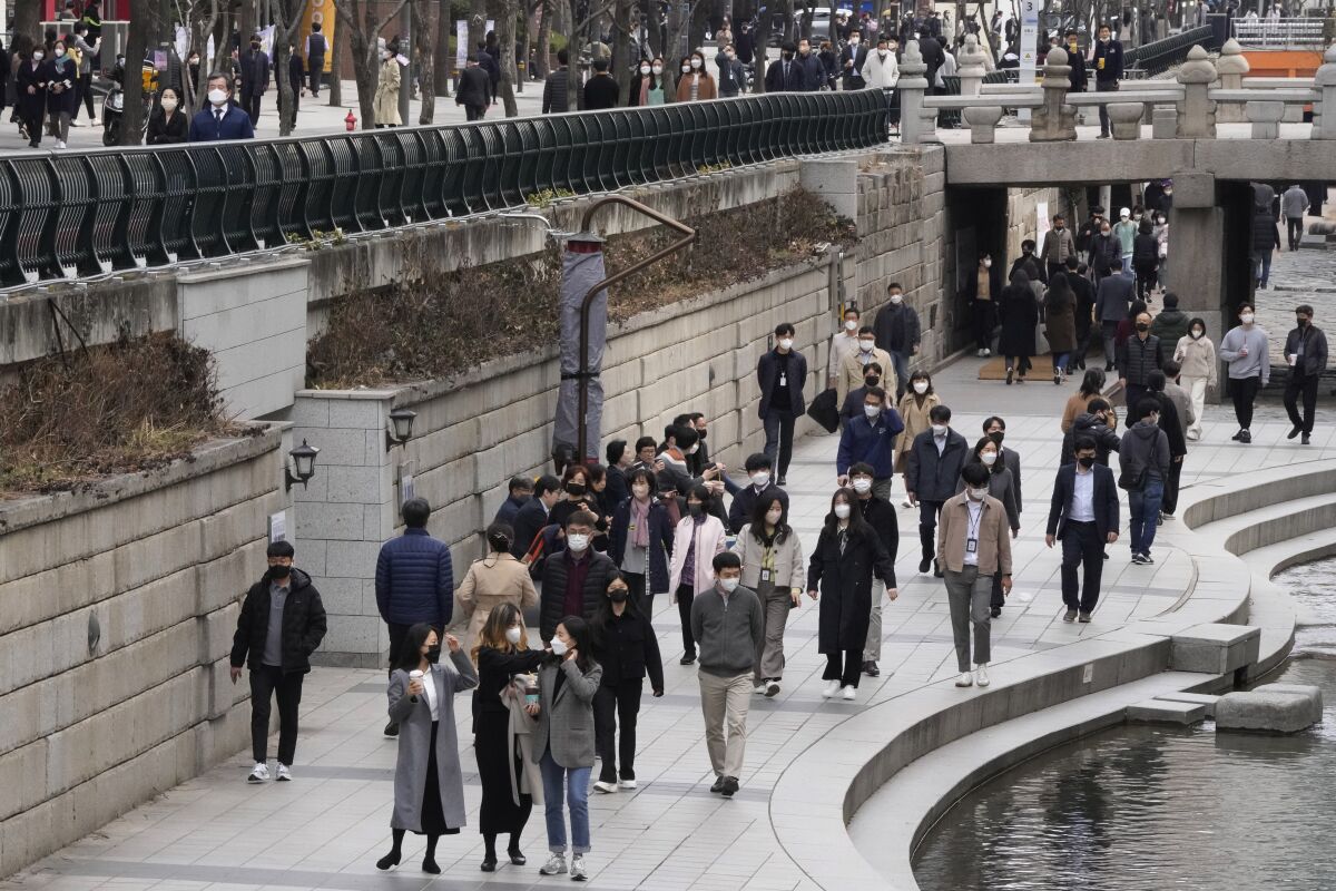 People wearing face masks as a precaution against the coronavirus walk at the Cheonggye Stream in Seoul, South Korea, Thursday, March 17, 2022. (AP Photo/Ahn Young-joon)