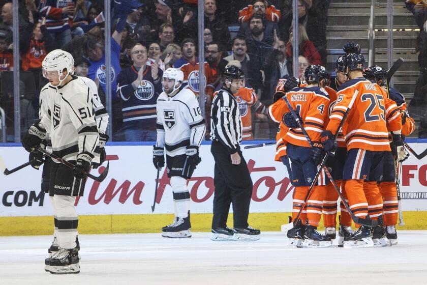 Los Angeles Kings' Austin Wagner (51) and Michael Amadio (10) skate past as the Edmonton Oilers celebrate a goal during the first period of an NHL game in Edmonton, Alberta, Tuesday, March 26, 2019. (Jason Franson/The Canadian Press via AP)