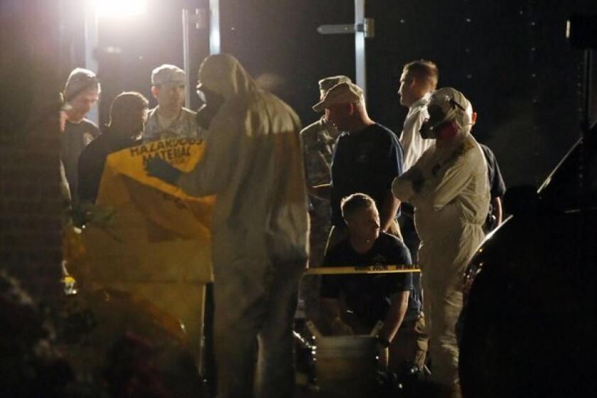 A federal agent wearing a hazmat suit secures a container used during a search of the Tupelo, Miss., home of James Everett Dutschke in connection with recent ricin-laced letters to U.S. officials.