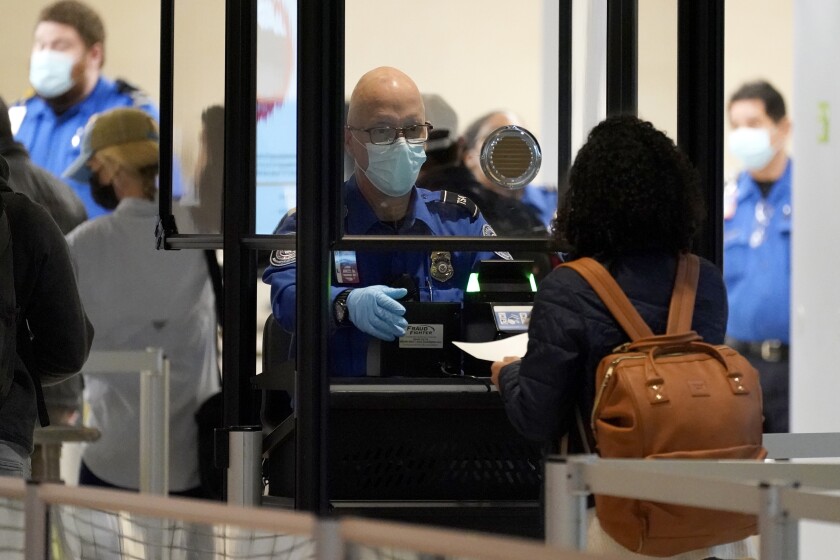 A TSA agent works with a traveler at a security checkpoint.
