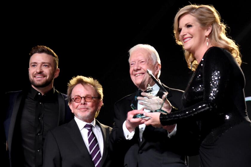 Justin Timberlake, left, along with Paul Williams, president of the American Society of Composers, Authors and Publishers, and former U.S. President Carter, present Trisha Yearwood with the Voice of Music award in Nashville on Monday.