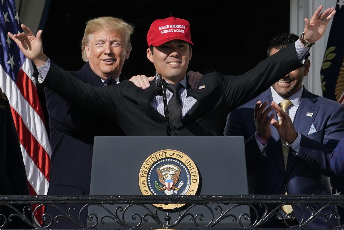 Washington Nationals catcher Kurt Suzuki wears a "Make America Great Again" hat as he is embraced by President Trump, with Nationals manager Davey Martinez looking on.