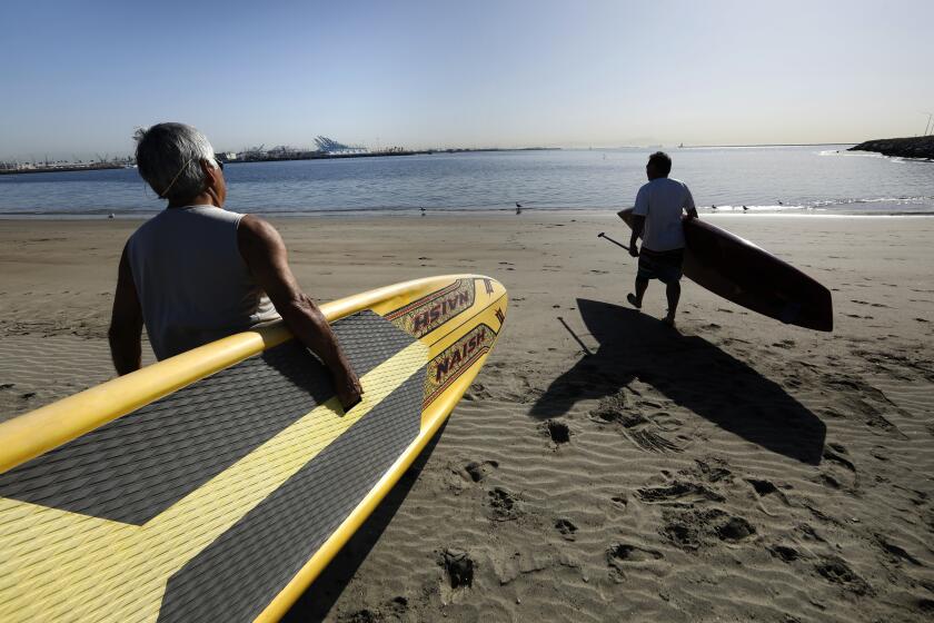 Los Angeles, California-April 7, 2022-Glenn Tawa, of San Pedro, left, and Kenny Miyamoto, of Torrance, head out on their paddle boards at Cabrillo Beach. A heat wave is on its way to hit Los Angeles starting today. At Cabrillo Beach in San Pedro, (Carolyn Cole / Los Angeles Times)