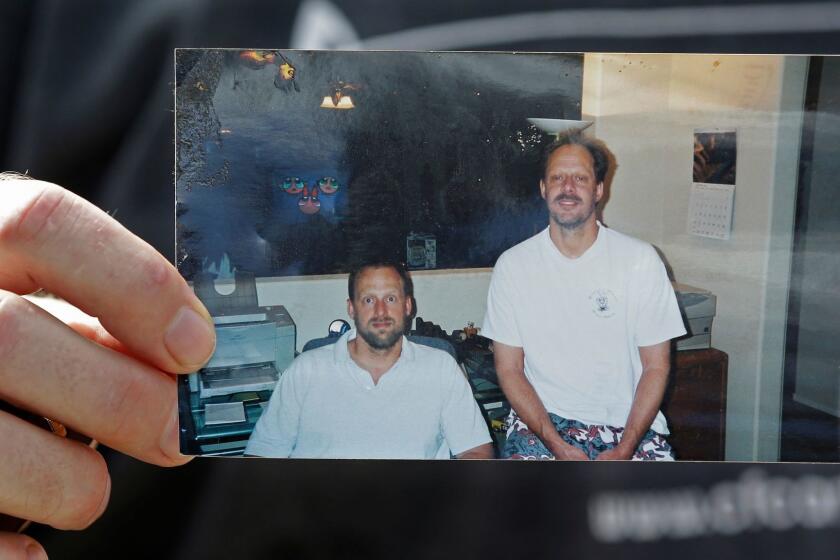 FILE - In this Oct. 2, 2017 file photo, Eric Paddock holds a photo of himself, at left, and his brother, Stephen Paddock, at right, outside his home in Orlando, Fla. A lawyer for Las Vegas police told a judge that charges could be filed in connection with the deadliest mass shooting in modern U.S. history, even though the gunman, Stephen Paddock, is dead. Attorney Nicholas Crosby was arguing Tuesday, Jan. 16, 2018, to keep search warrants sealed. (AP Photo/John Raoux, File)