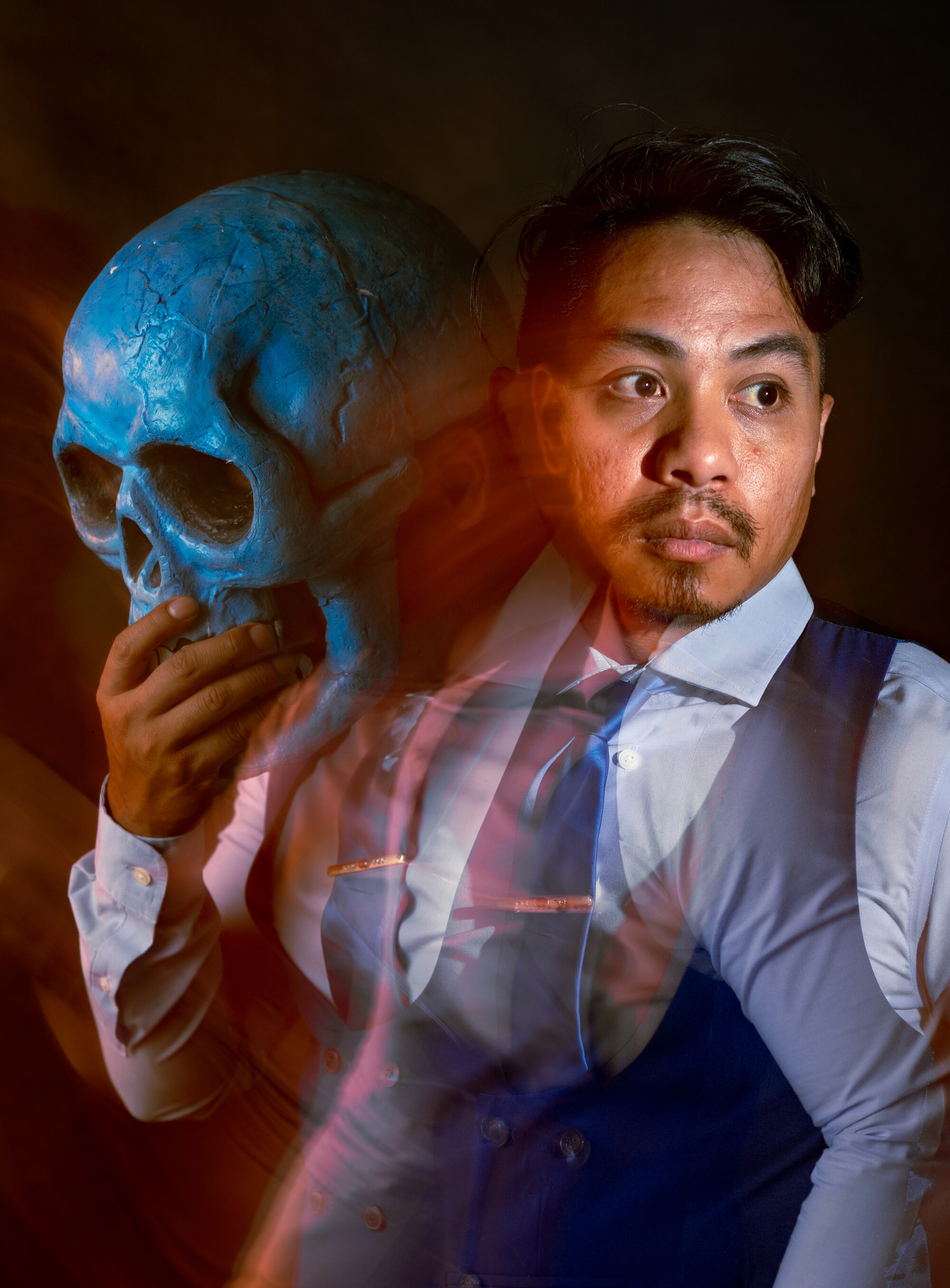 A long exposure image of a man holding a skull mask.