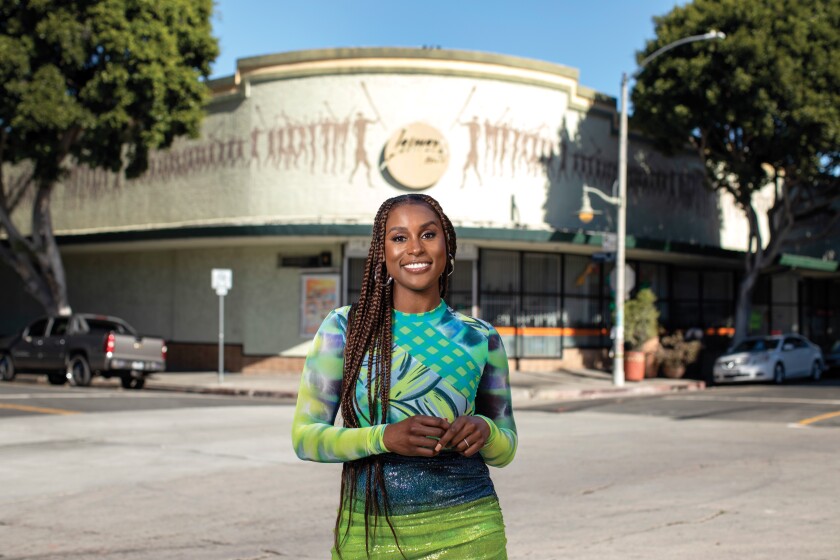"Insecure" star Issa Rae stands in front of a community art center in a bright blue and green dress.