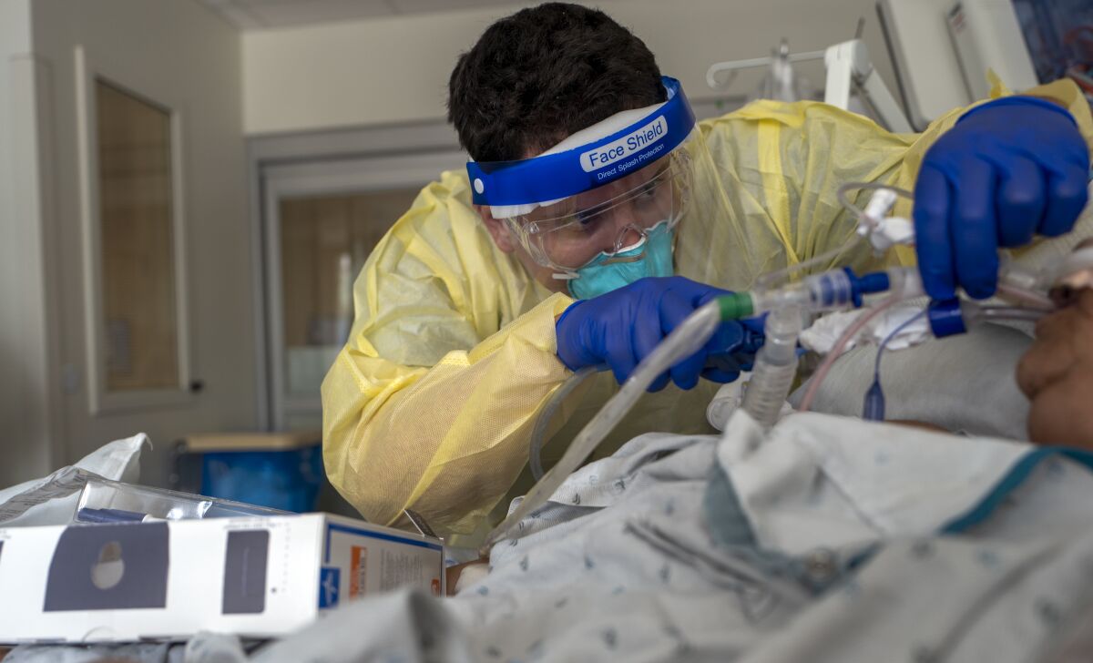 A respiratory therapist works with a COVID-19 patient.