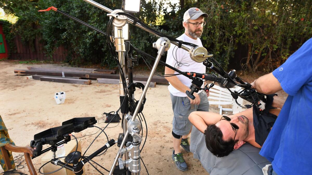 Cinematographer Jeff Fitzpatrick prepares for a shoot with a virtual reality camera as actor Ryan Driller waits patiently on the set of a porn production in Woodland Hills.
