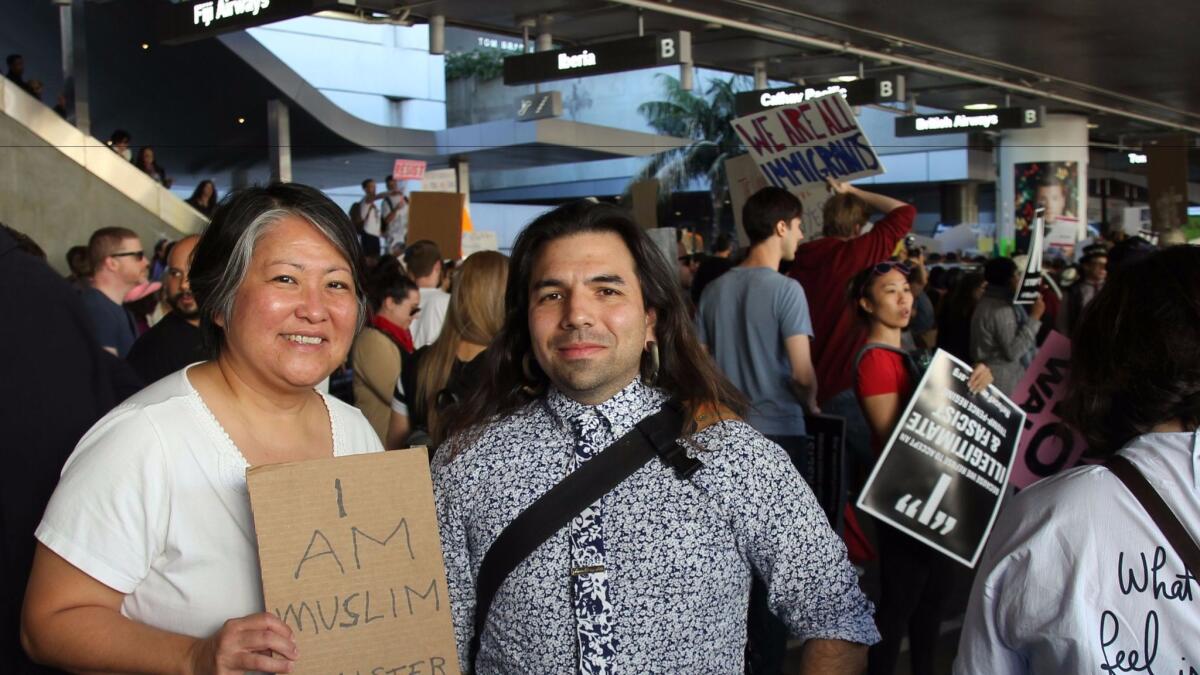 Arts writer Carol Cheh and artist and administrator Marshall Astor protest Trump's travel ban at Tom Bradley International Terminal at LAX.