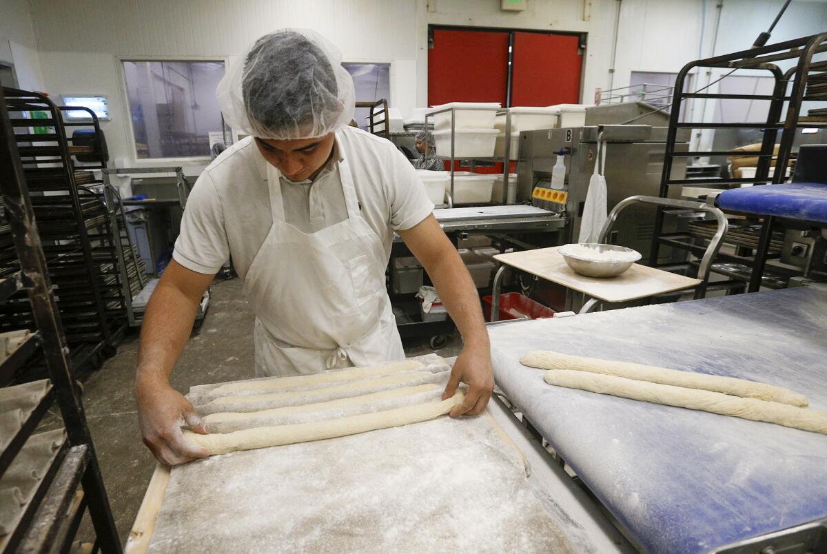 Baker Ben Ramirez rolls baguettes for the oven at the Bread Artisan Bakery in Santa Ana.