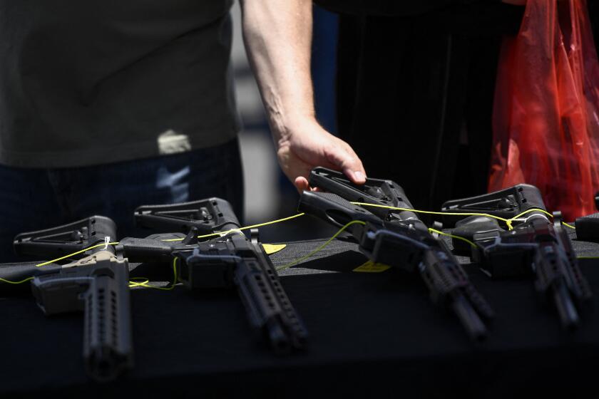 A customer examines a Valor Industries LLC California-compliant AR-15 style rifle displayed for sale at a vendor booth at the Crossroads of the West Gun Show at the Orange County Fairgrounds on June 5, 2021 in Costa Mesa, California. - Gun sales increased in the US following Covid-19 pandemic lockdowns. On June 4, a San Diego federal court judge overturned California's three-decade old ban on assault weapons, defined as a semiautomatic rifle or pistol with a detachable magazine and certain features, but granted a 30-day stay for a State appeal and likely future court decisions on the constitutionality of the ban under the Second Amendment. An industry of California legal "featureless" or "compliant" AR-15 style rifles developed for California consumers, adapting to the law with design changes to the popular rifle. (Photo by Patrick T. FALLON / AFP) (Photo by PATRICK T. FALLON/AFP via Getty Images)
