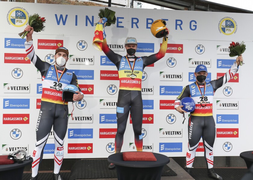 From left, second-placed Nico Gleirscher of Austria, first-placed Johannes Ludwig of Germany and third-placed Wolfgang Kindl of Austria stand on the podium after the men's single-seater in the Luge World Cup in Winterberg, Germany, Saturday, Jan. 1, 2022. (Friso Gentsch/dpa via AP)