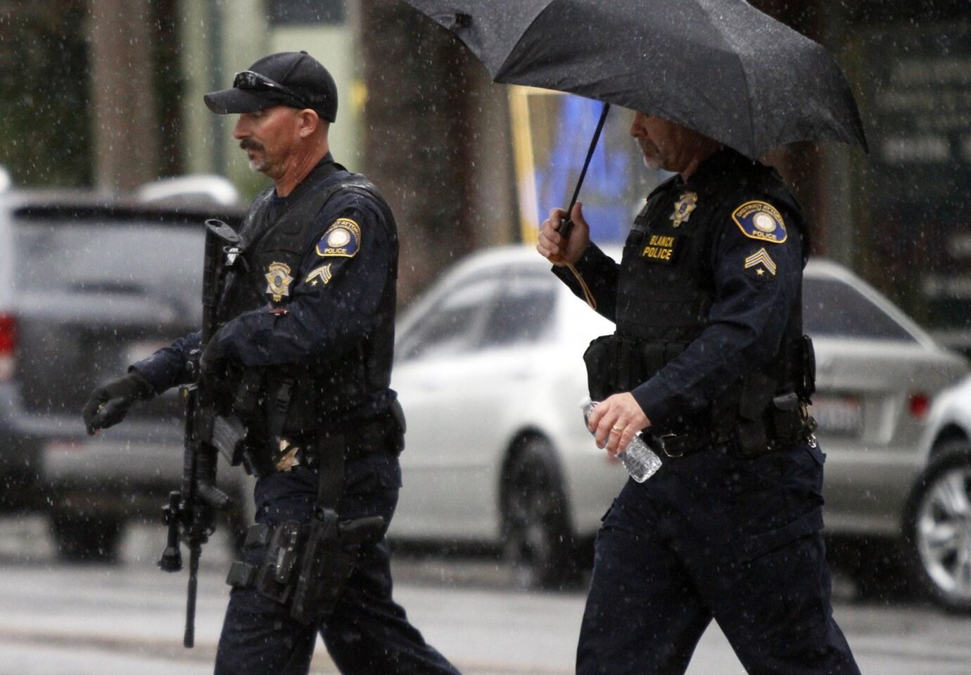 Riverside district attorney's office investigators patrol in heavy rain around their headquarters on Friday morning in Riverside.