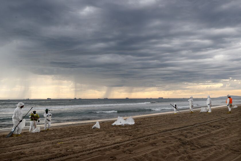 HUNTINGTON BEACH, CALIFORNIA - OCTOBER 04: Cleanup workers in protective suits prepare to depart the closed Huntington State Beach as a storm approaches after a 126,000-gallon oil spill from an offshore oil platform on October 4, 2021 in Huntington Beach, California. The spill forced the closure of the popular Great Pacific Airshow yesterday with authorities closing beaches in the vicinity. (Photo by Mario Tama/Getty Images)