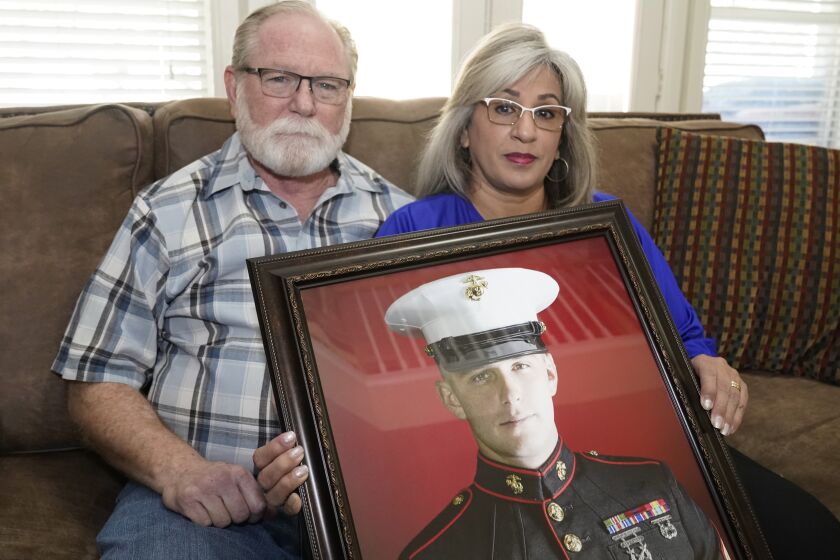 FILE - Joey and Paula Reed pose for a photo with a portrait of their son, Marine veteran and Russian prisoner Trevor Reed, at their home in Fort Worth, Texas, Feb. 15, 2022. Negotiations between the U.S. and Russia led to basketball star Brittney Griner's return to the U.S. on Friday, Dec. 9, 2022, in exchange for notorious arms dealer Viktor Bout. It is the latest in a series of high-profile prisoner swaps involving Americans detained abroad, one of whom was Reed, an American imprisoned in Russia for nearly three years. He was swapped for Konstantin Yaroshenko, a Russian pilot who had been serving a 20-year federal sentence for conspiring to smuggle cocaine into the U.S. (AP Photo/LM Otero, File)