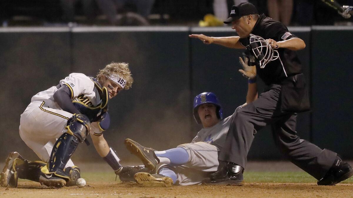 UCLA's Jake Moberg scores the go-ahead run in front of Michigan catcher Joe Donovan during the 12th inning of the Bruins' 5-4 victory in an NCAA super regional on June 8.