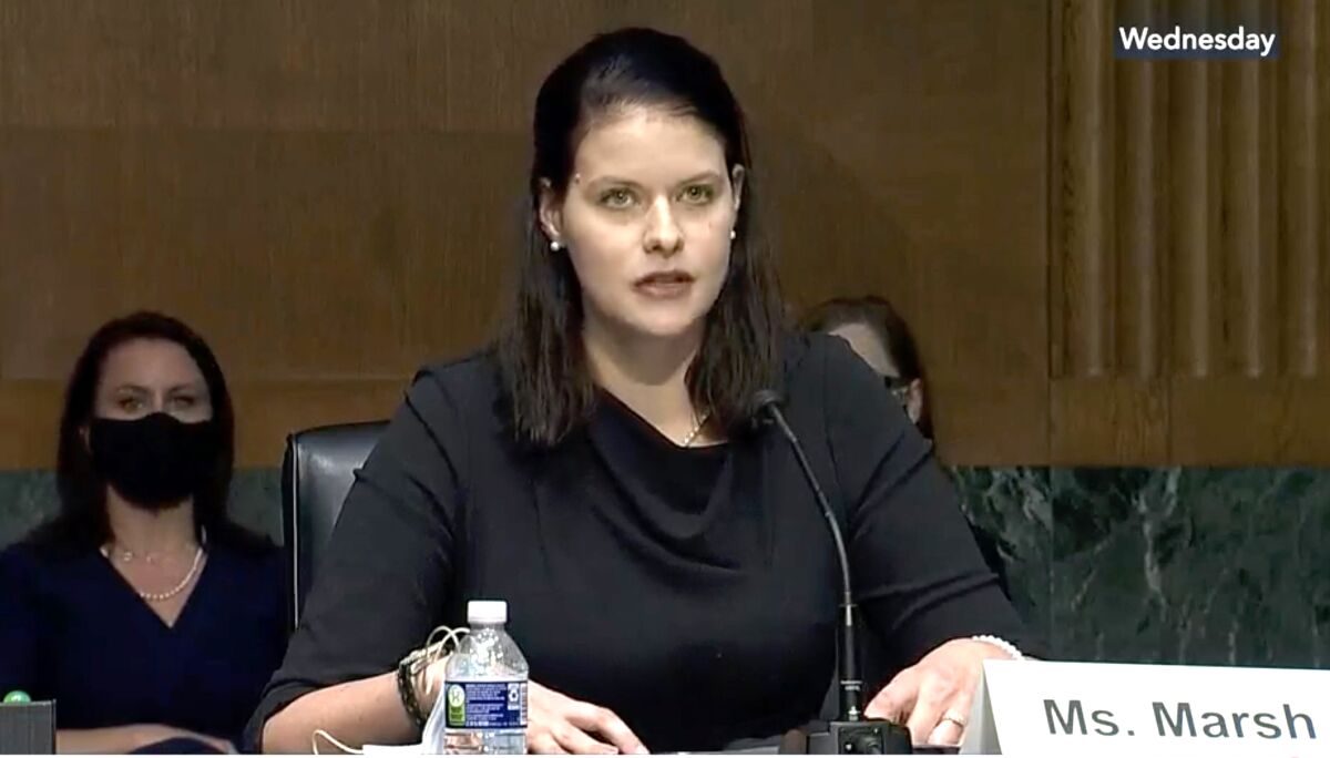 Amy Marsh sits and speaks into a microphone in a hearing room.