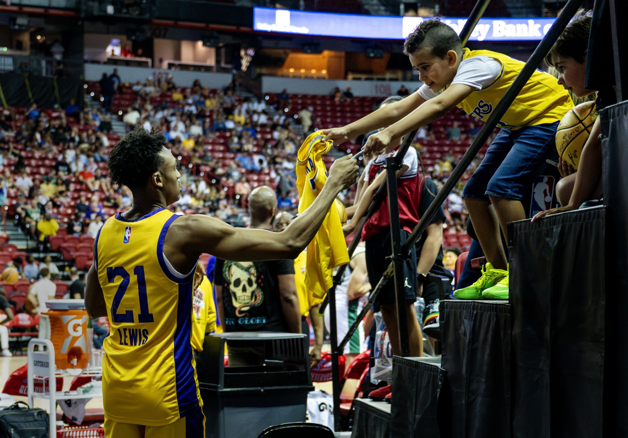 Maxwell Lewis, bir NBA Yaz Ligi maçı sırasında genç bir Lakers taraftarına imza atıyor.