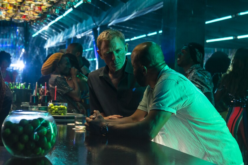 Two men talk in a dimly lighted bar.