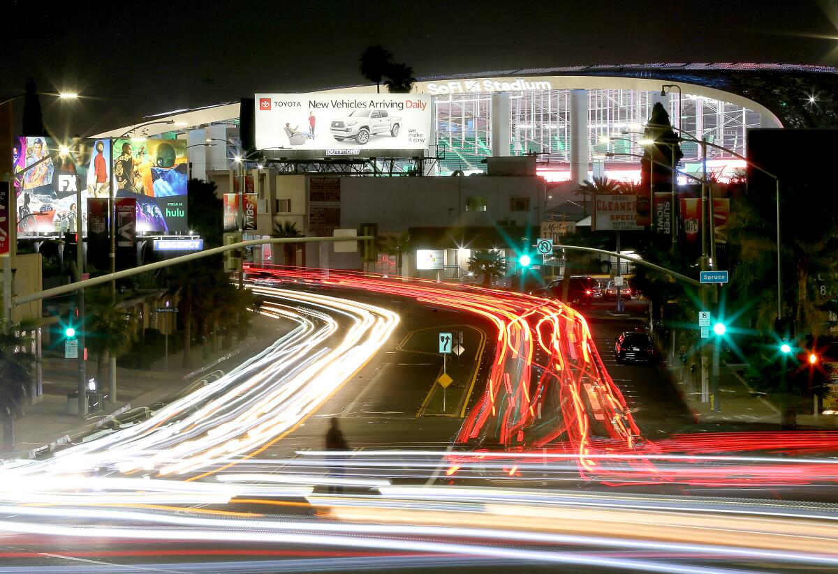 Streaks from headlights and taillights on a road outside SoFi Stadium at night