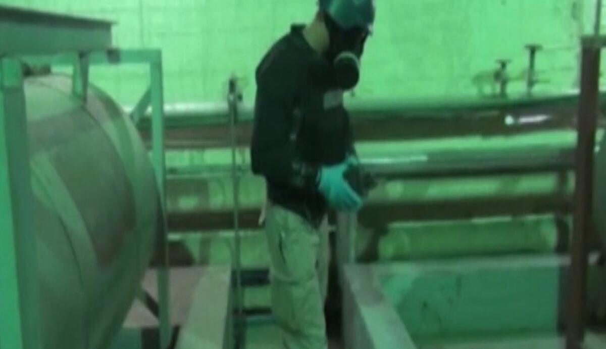 An image taken from Syrian television shows an inspector from the Organization for the Prohibition of Chemical Weapons at work at an undisclosed location in Syria on Tuesday.