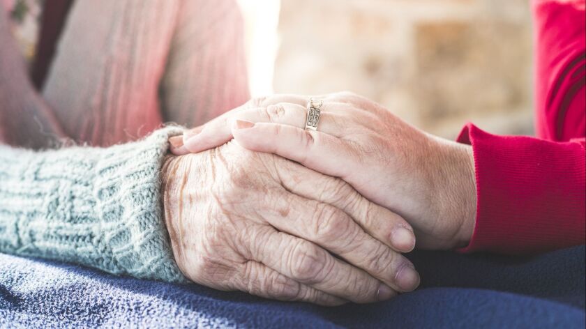 A stock photo of an Elderly woman holding hands with her younger family members