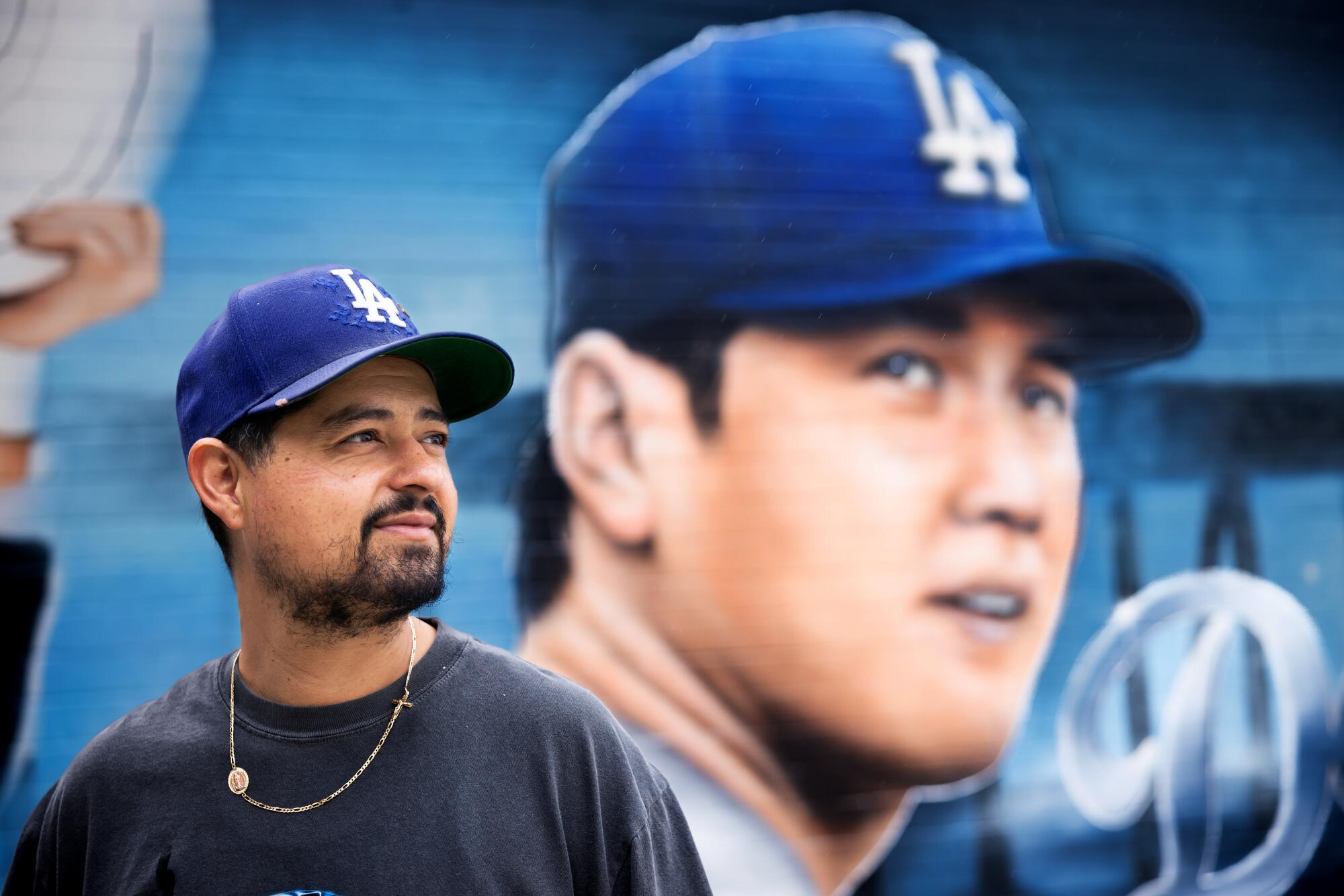 Artist Gustavo Zermeo Jr. stands in front of his mural featuring newest Dodger player Shohei Ohtani