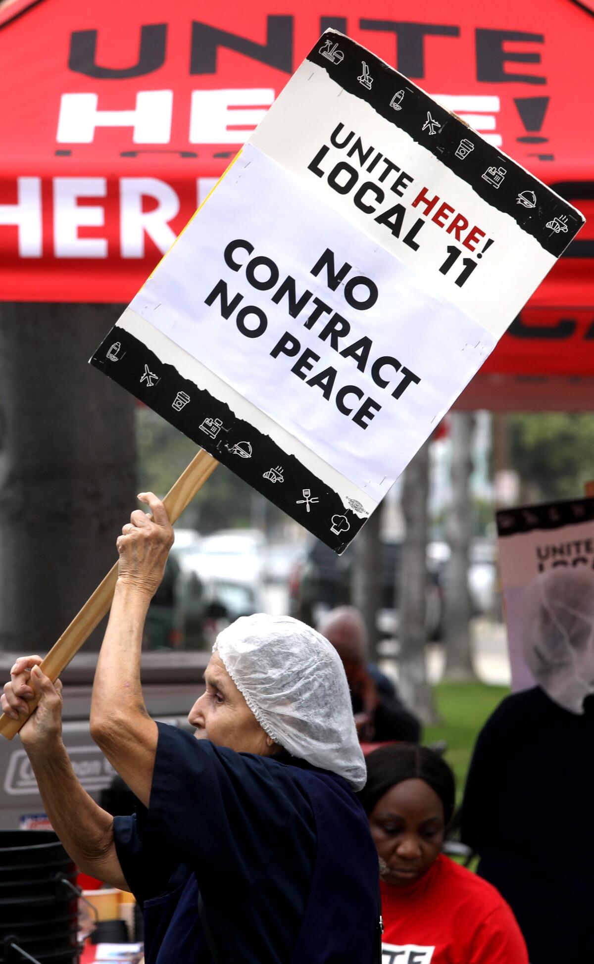 A woman carries a sign while picketing with her co-workers.